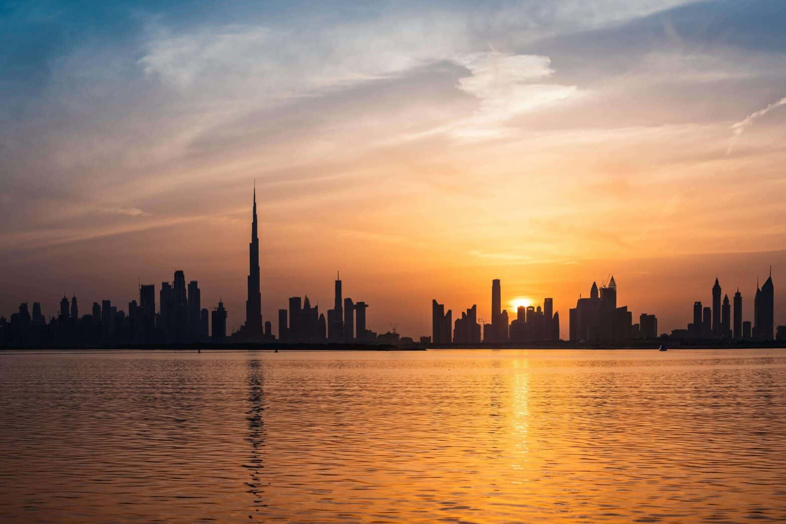 Dubai skyline at sunset seen from the water.
