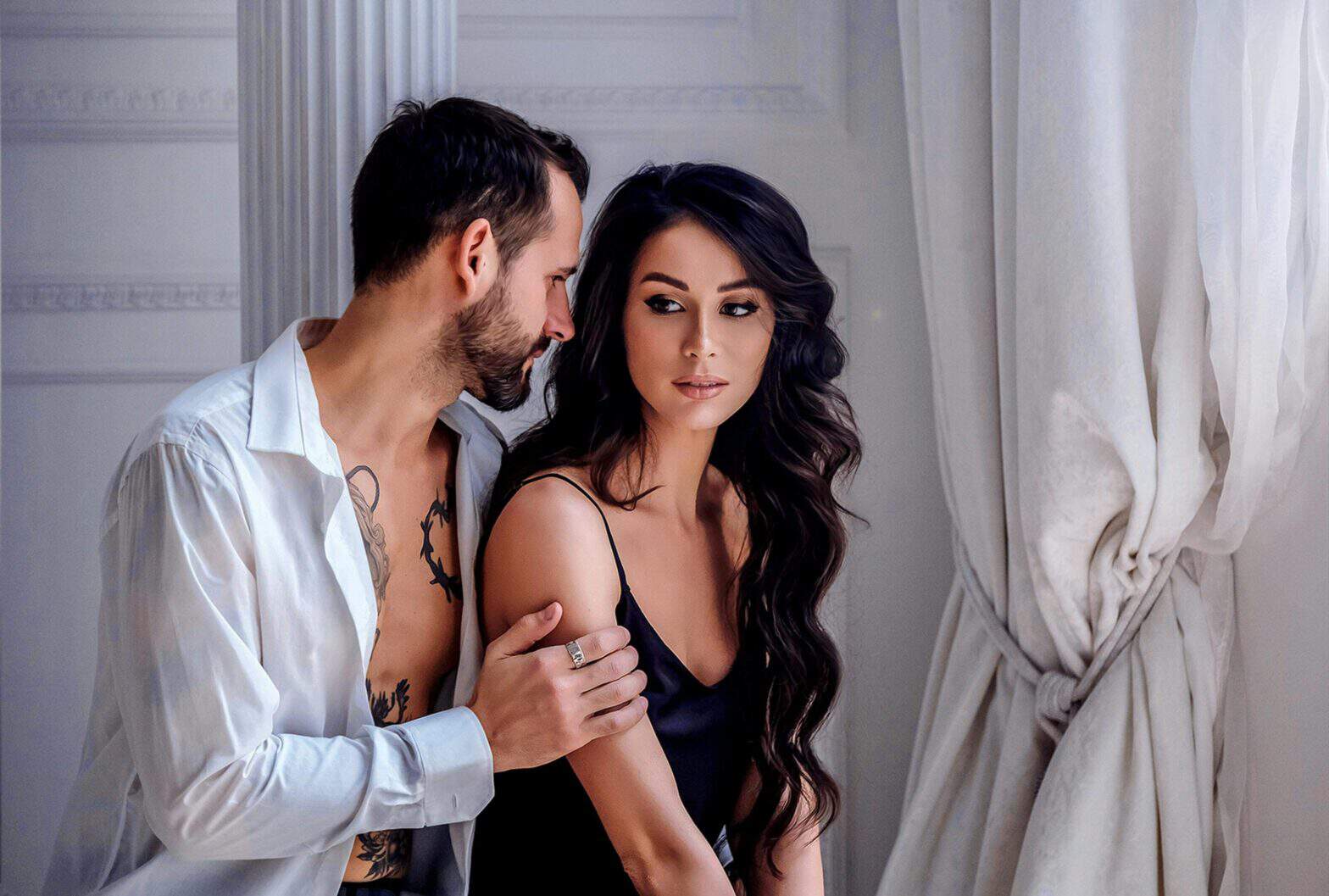 An escort and a client sitting on a bed talking