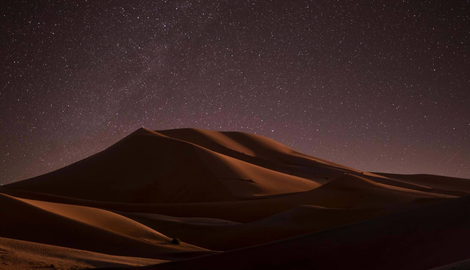 a starry sky over a desert landscape in Dubai