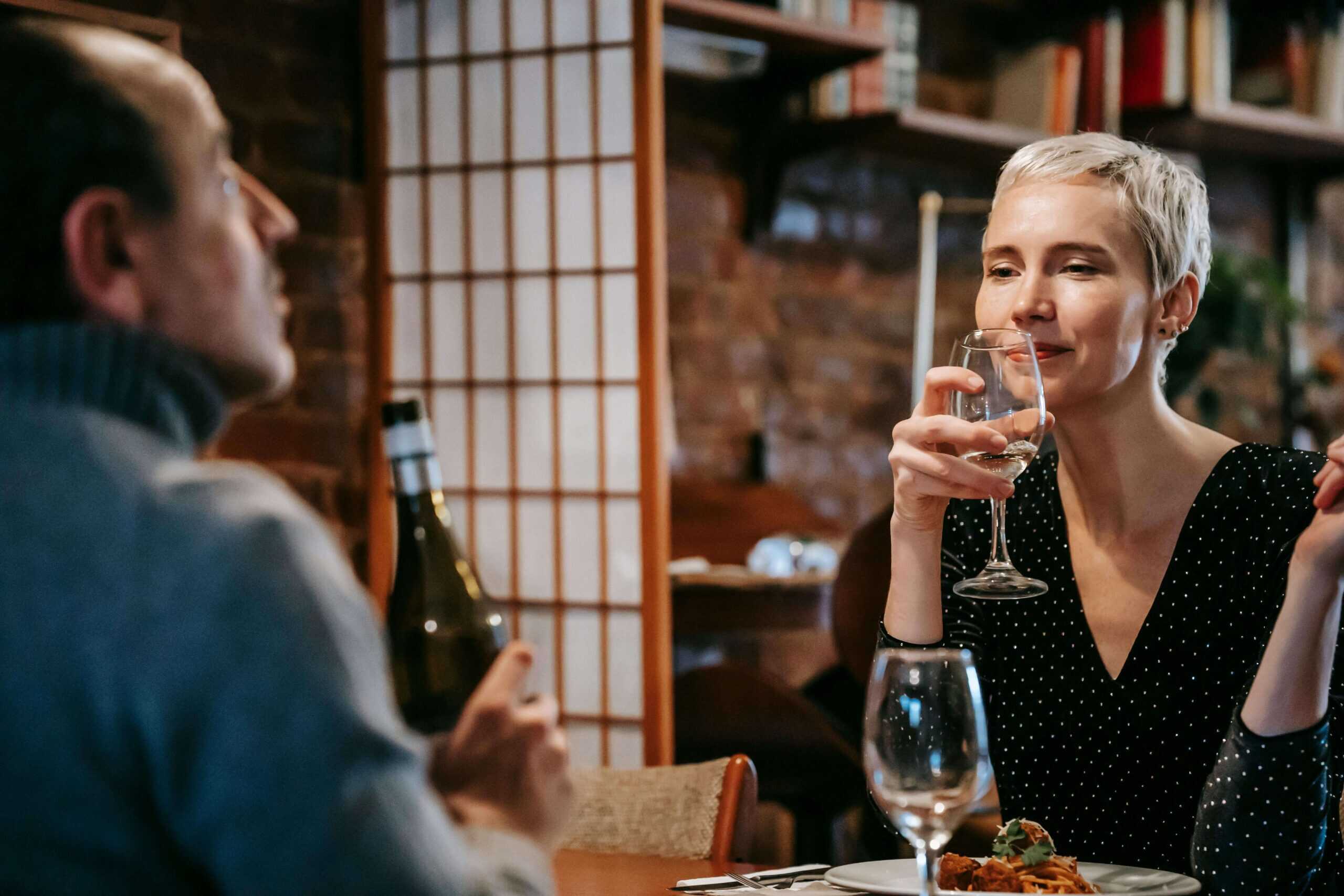 an escort and her client drinking wine in a restaurant