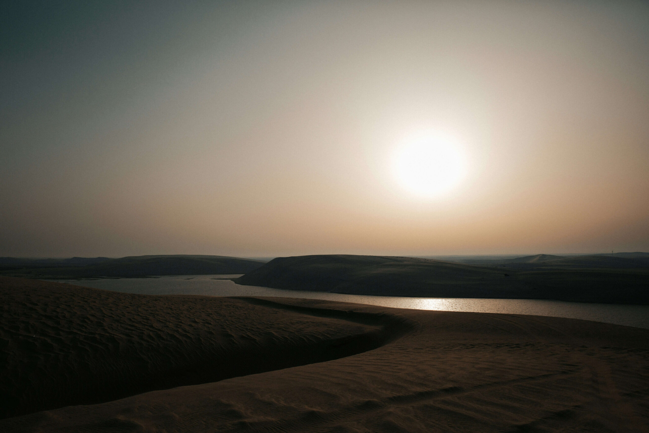 the sun rising over desert sand dunes in Doha